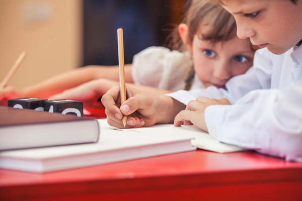 Niña observando a niño hacer los deberes