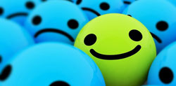Emoticono sonriente entre emoticonos tristes